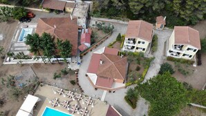 Vue aérienne d’un complexe hôtelier comprenant plusieurs bâtiments, une piscine et un court de tennis.
