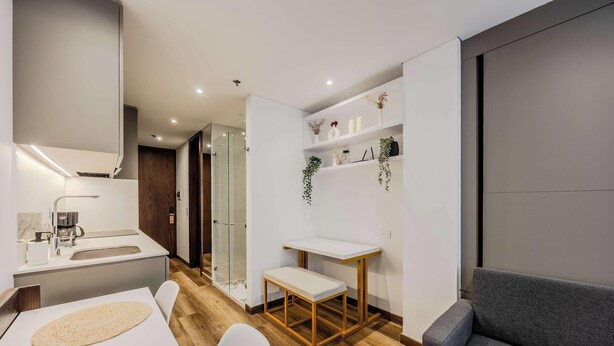 A modern bathroom with a shower, a sink, and a bench. - NOK Stylish Stay in Parque 93 (Bogotá)