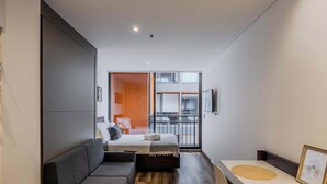 A modern hotel room with a bed, a sofa, a dining table, and a balcony with a view. - NOK Stylish Stay in Parque 93 (Bogotá)