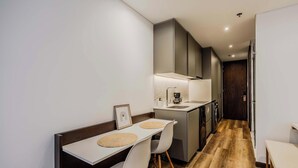 A modern kitchen with a dining area, wooden flooring, and a dark wooden door. - NOK Stylish Stay in Parque 93 (Bogotá)