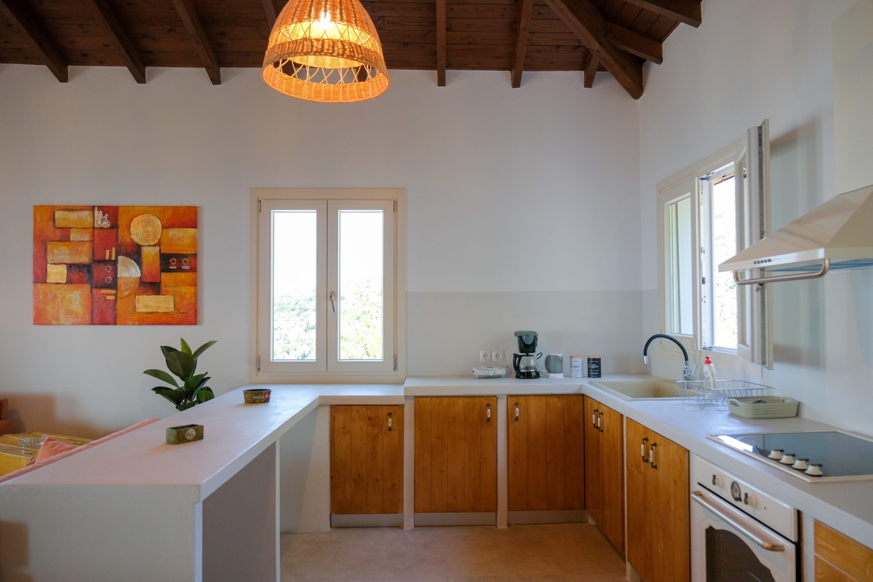 A kitchen with wooden cabinets, a white countertop, a hanging light fixture, and a window.
