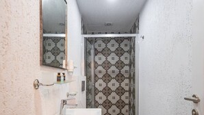 A bathroom with a sink, mirror, towel rack, and patterned shower area. - Taksim Square - 1BR Deluxe Suite 101 (Istanbul)