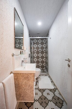 Ein Badezimmer mit Waschbecken, Spiegel, Handtuchhalter und einer Dusche mit Muster.