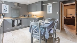 A modern kitchen with grey cabinets, a wooden countertop, and a dining table set for four. - Cosy Stone Cottage In Gargrave Near Skipton (Skipton)