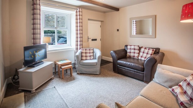 A living room with a television, two armchairs, a sofa, a small table, and a window with curtains. - Cosy Stone Cottage In Gargrave Near Skipton (Skipton)