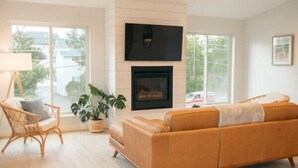 A living room with a sofa, a chair, a fireplace, and a large window. - Park Point Lagom, Heirloom Vacations (Duluth)