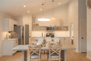 A modern kitchen with a dining area, featuring a central island, pendant lighting, and built-in appliances. - Park Point Scandinavian Home, Heirloom Vacations (Duluth)