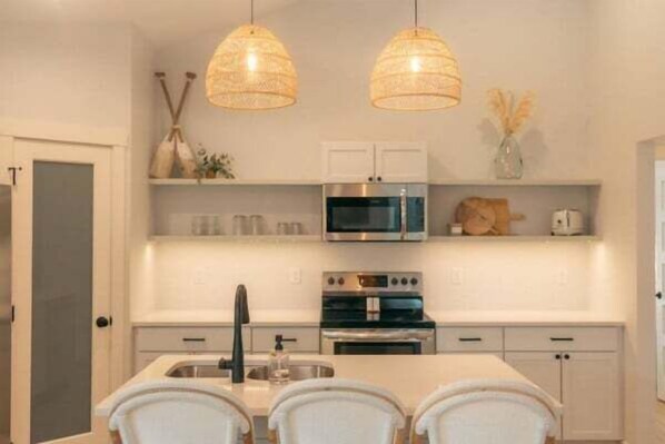 A modern kitchen with white cabinetry, stainless steel appliances, and pendant lighting. - Park Point Scandinavian Home, Heirloom Vacations (Duluth)