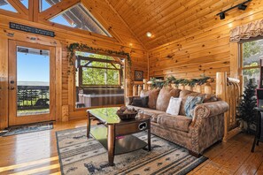 Ein Holzblockbau-Innenraum mit einer Couch, einem Couchtisch und Blick durch die Tür.