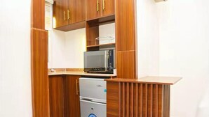 Een kleine keuken met een magnetron, koelkast en houten kastjes.