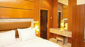 Een hotelkamer met een bed, een houten garderobe, een spiegel en een kaptafel met lamp.