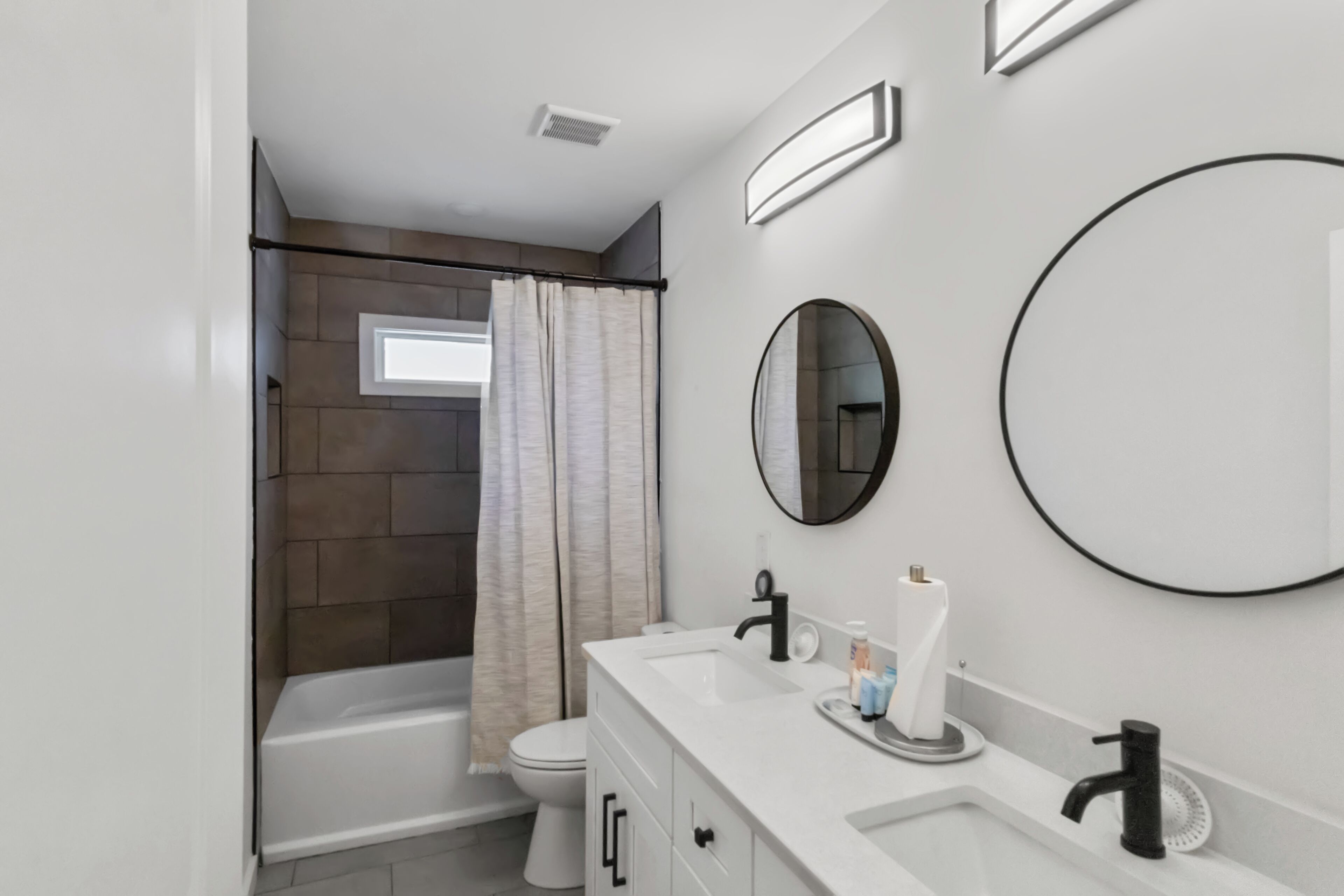 Un bagno moderno con vasca, servizi igienici e un mobile lavabo con lavandino e specchio.