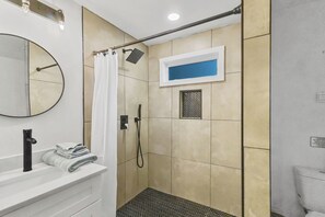 Ein Badezimmer mit Dusche, Waschbecken, Spiegel und Handtuchhalter.