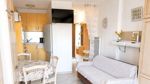 En kompakt bolig med et tekøkken, et spisebord og en sofa.