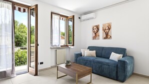 Ein Wohnzimmer mit einer Couch, einem Couchtisch, einer Schiebetür aus Glas und zwei Wandbildern.