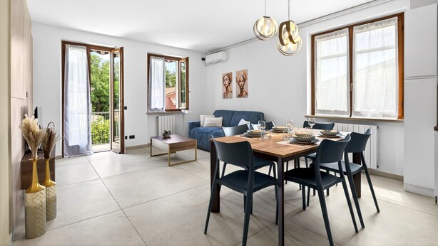 Ein modernes Wohnzimmer mit Essbereich, großen Fenstern und Blick ins Grüne.