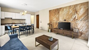Ein modernes Wohnzimmer mit einer Couch, einem Couchtisch, einem Fernseher und einem Essbereich mit Stühlen und einem Tisch.
