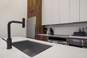 A modern kitchen with a stainless steel refrigerator, a black faucet, and a built-in oven.