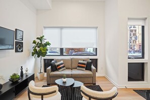 A modern living room with a sofa, two armchairs, a coffee table, and a large window with blinds. - Downtown DC Gem | Minutes to Convention Center (Washington)