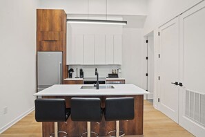 A modern kitchen with a central island, white cabinetry, and a built-in oven. - Downtown DC Gem | Minutes to Convention Center (Washington)
