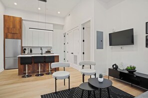 A modern kitchen with white cabinets, a built-in fridge, and a bar area with stools.