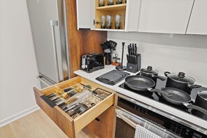 Una cocina moderna con tostadora, sartén, ollas y un organizador de cajones.