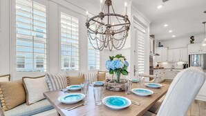 A dining room with a long table set for six, a chandelier, and a view of the kitchen. - 🦩Book Me Baby! Seaesta in Prominence🦩 (Inlet Beach)