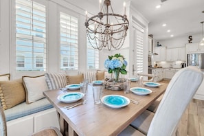 A dining room with a long table set for six, a chandelier, and a view of the kitchen. - 🦩Book Me Baby! Seaesta in Prominence🦩 (Inlet Beach)