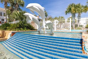 Ein Pool mit blauen Stufen und weißen Delfin-Skulpturen.