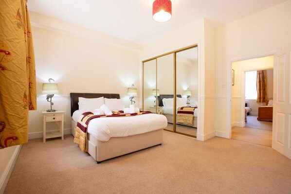 A bedroom with a bed, bedside tables, a mirror, and a wardrobe. - Spacious Historic Home In Cockermouth With Parking (Cockermouth)
