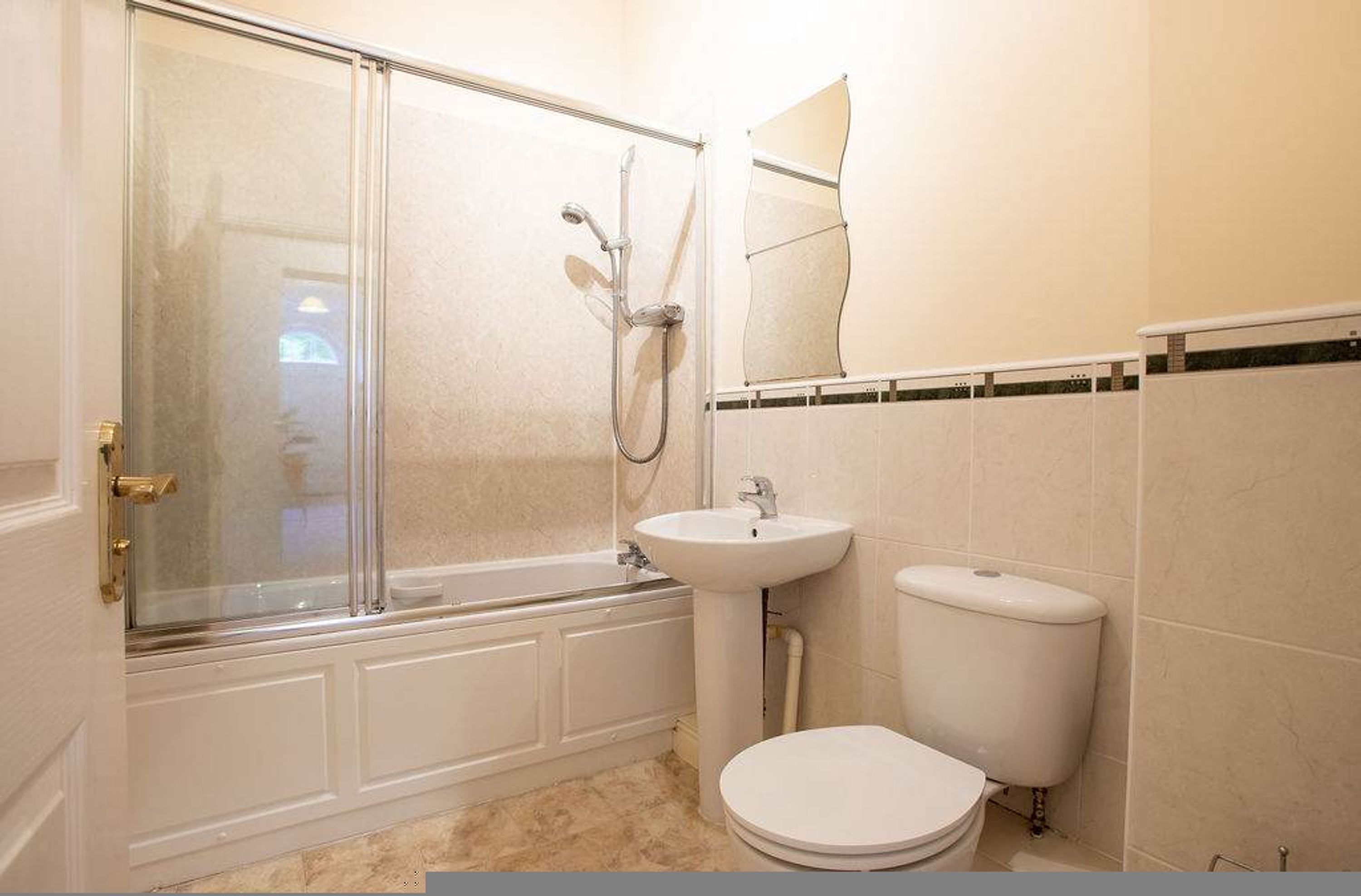 Un baño con ducha de vidrio, lavabo e inodoro.