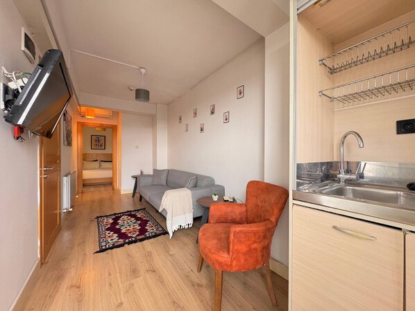 A compact living space with a kitchenette, a sofa, a chair, and a small dining table. - Taksim Square-1br Rooftop Suite 07 (Istanbul)