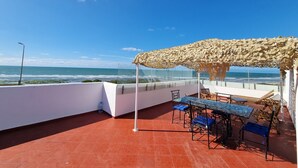 Eine Terrasse mit Tisch und Stühlen, einer Pergola und Blick auf das Meer.