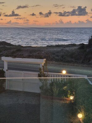 A coastal view with a body of water, a white fence, and a pathway leading to a building. - Studio seaside terrace panoramic ocean view (El Jadida)