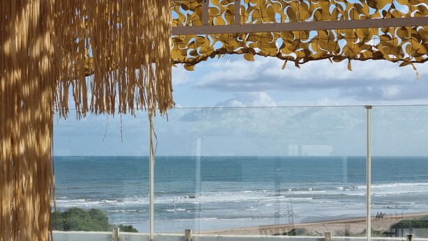 Ein Balkon mit Blick auf das Meer, einer Betonbrüstung und einem Metallgeländer.