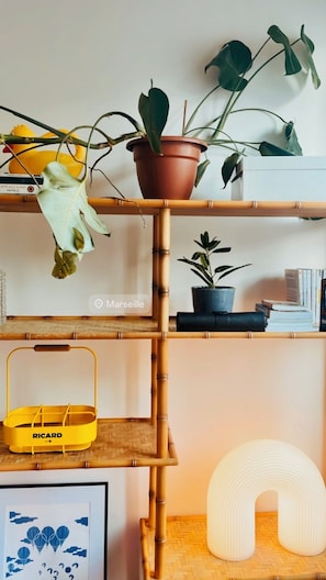 A bamboo shelf with potted plants, a yellow basket, and a framed picture. - Typical sunny apartment in Notre-Dame du Mont with balcony and air conditioning (Marseille)