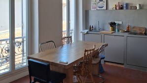 Une cuisine moderne avec un coin repas, de grandes fenêtres et un luminaire suspendu.
