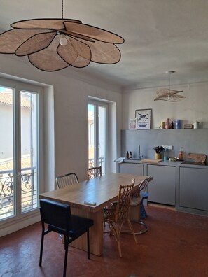 A modern kitchen with a dining area, large windows, and a hanging light fixture. - Typical sunny apartment in Notre-Dame du Mont with balcony and air conditioning (Marseille)