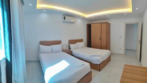 Une chambre d’hôtel avec deux lits, une armoire, un appareil de climatisation et une fenêtre avec des rideaux.