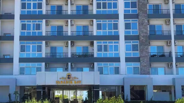 Un hôtel à plusieurs étages, reconnaissable à son grand panneau indiquant « FANADIR BAY », doté de balcons et de climatiseurs.
