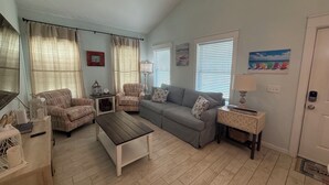 Ein Wohnzimmer mit Sofa, Sesseln, Couchtisch und Deckenventilator.