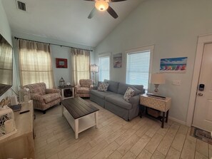 Ein Wohnzimmer mit Sofa, Sesseln, Couchtisch und Deckenventilator.