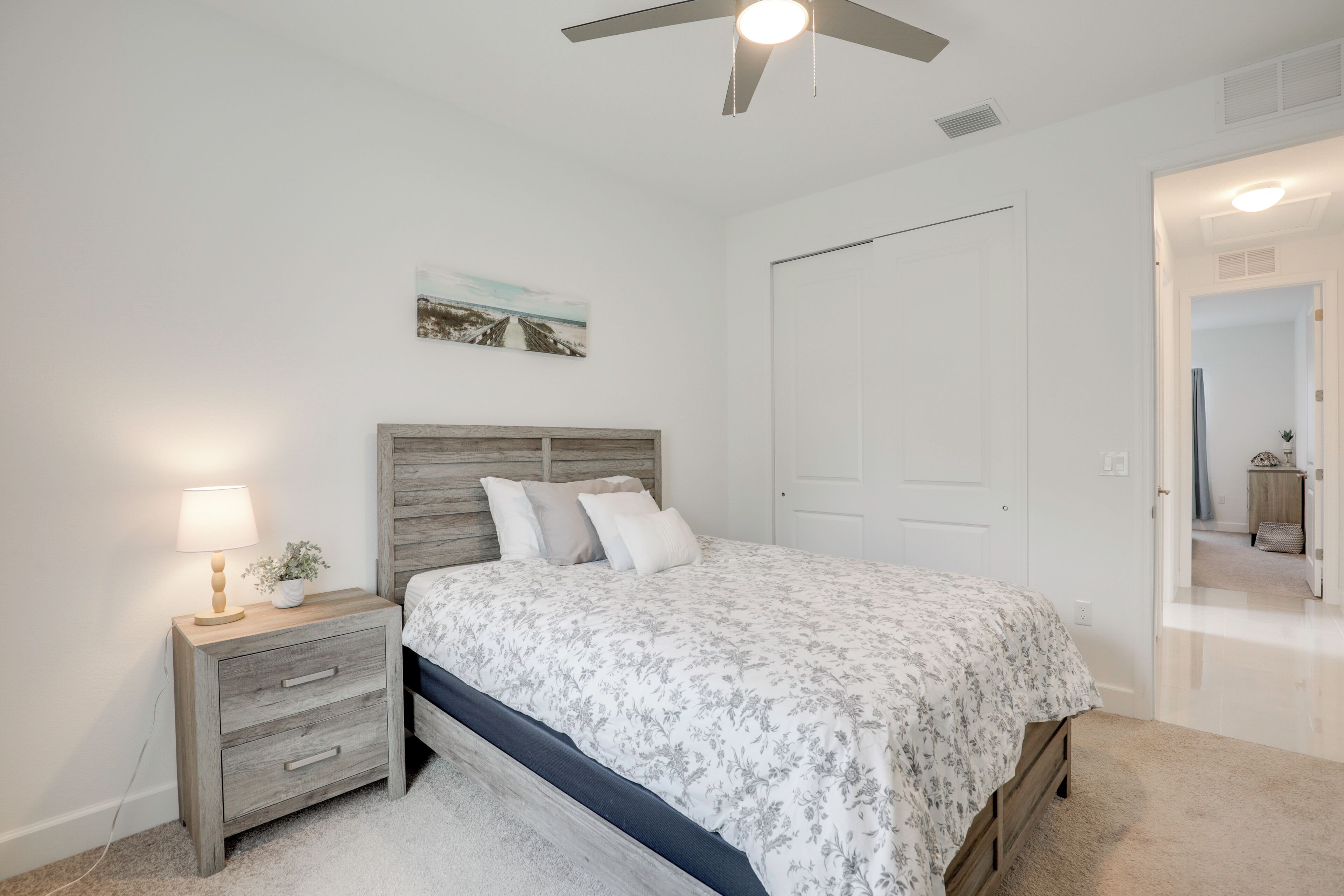 Une chambre à coucher avec un lit, une table de chevet, une lampe et un ventilateur de plafond.
