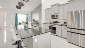 A modern kitchen with stainless steel appliances, a central island, and white cabinetry. - Private Outdoor Oasis! Home 12 Mi to Flagler Beach (Palm Coast)