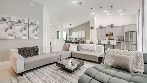 A modern living room with a sectional sofa, a coffee table, and a dining area with a kitchen in the background. - Private Outdoor Oasis! Home 12 Mi to Flagler Beach (Palm Coast)