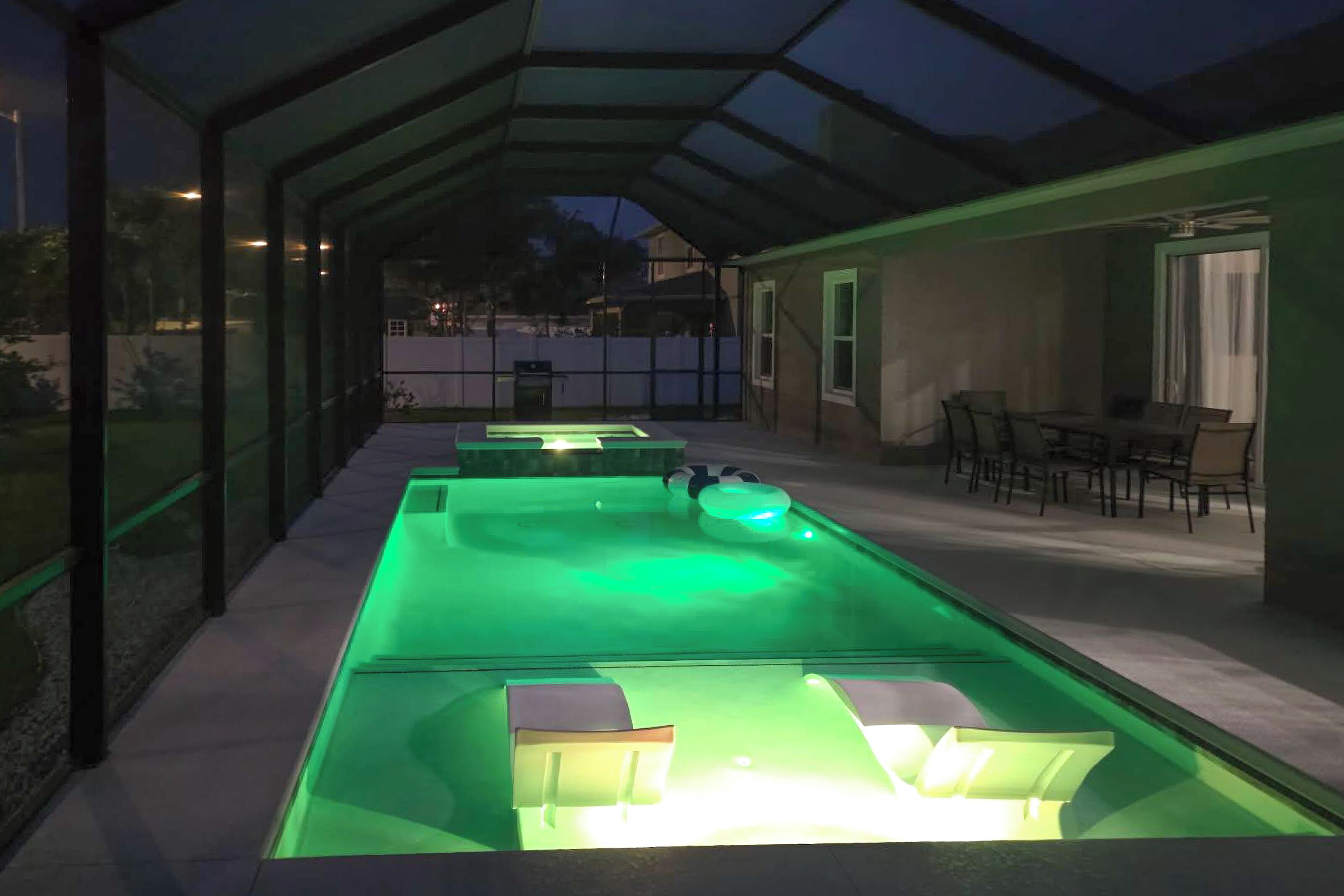 Ein Poolbereich mit Glasveranda, Sitzgelegenheiten und Deckenventilator.