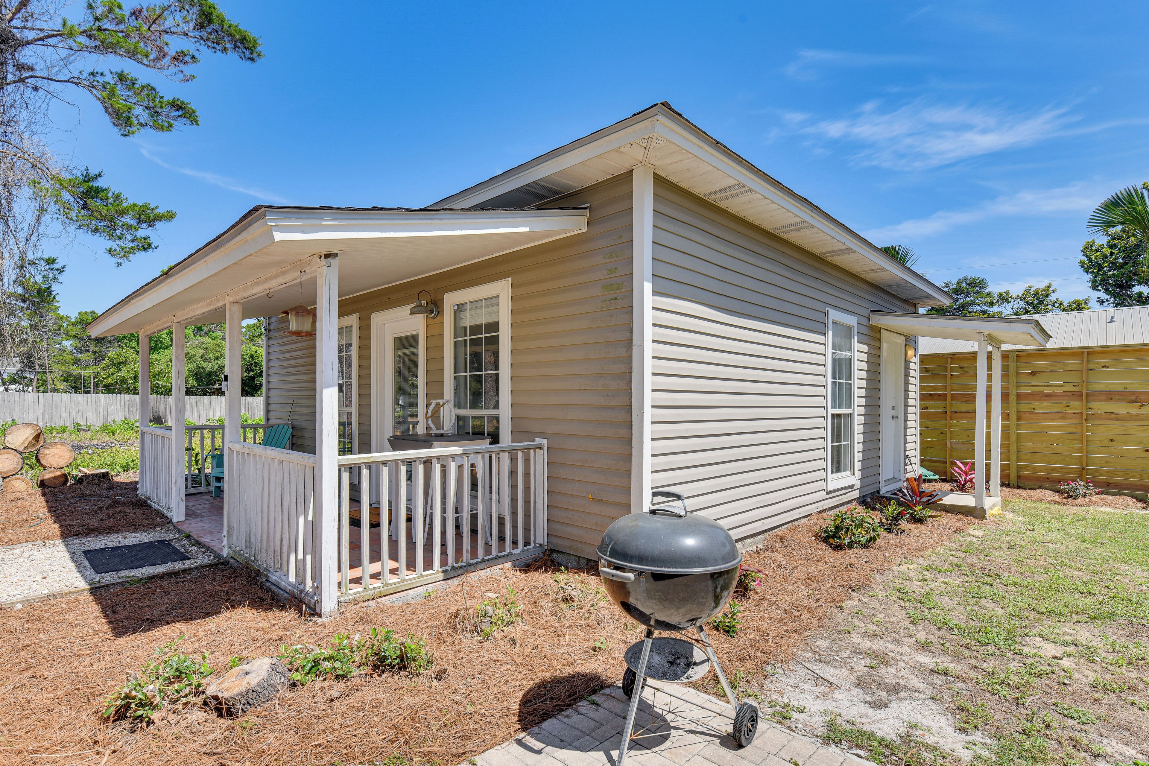 A single-story house with a covered porch, a barbecue grill, and a fenced yard.