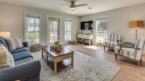 A spacious living room with a sofa, armchair, coffee table, and a television. - Walk to Ocean & Eats: Santa Rosa Beach Cottage (Santa Rosa Beach)