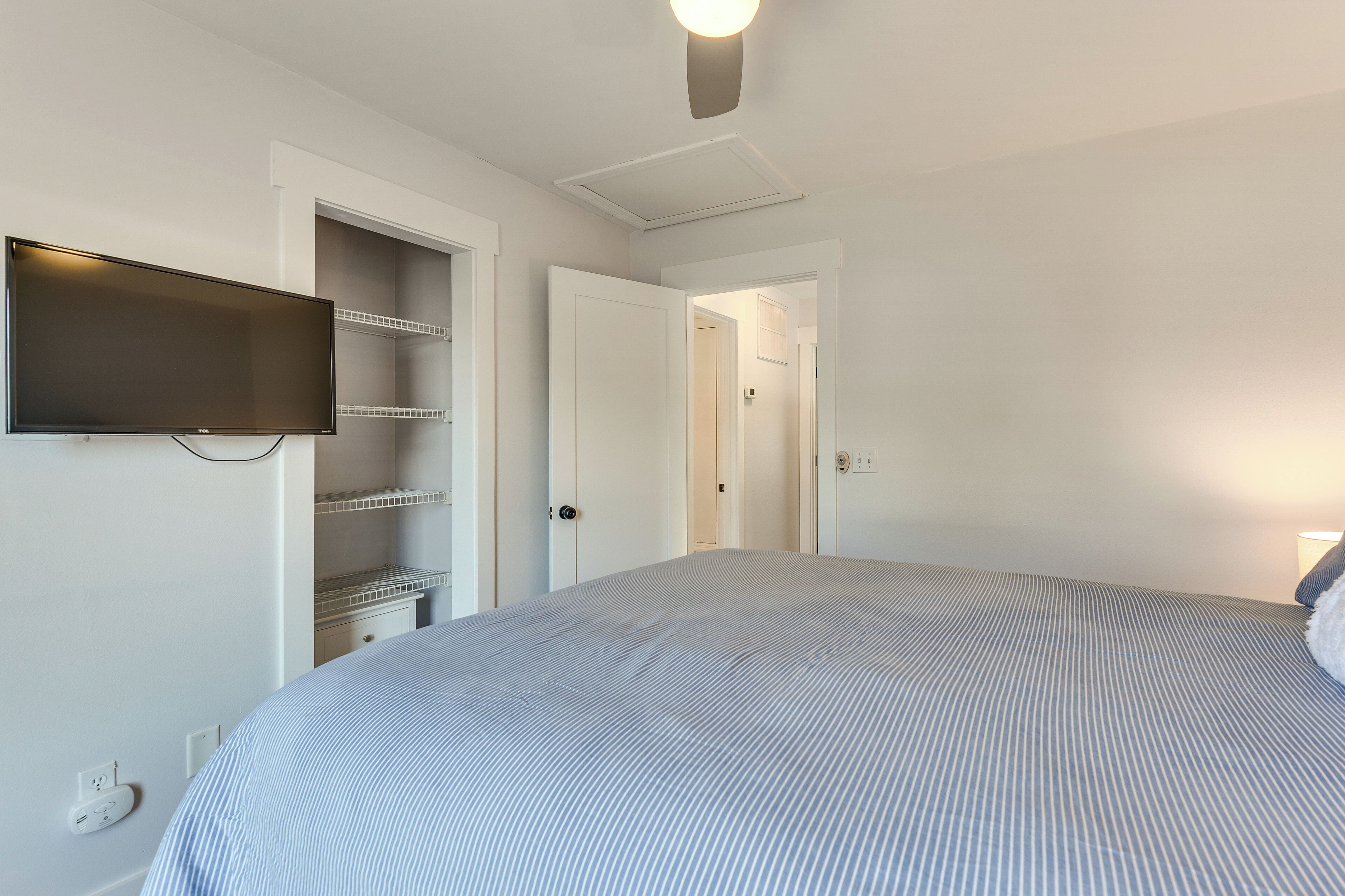 A bedroom with a bed, a TV mounted on the wall, and a door leading to a closet.