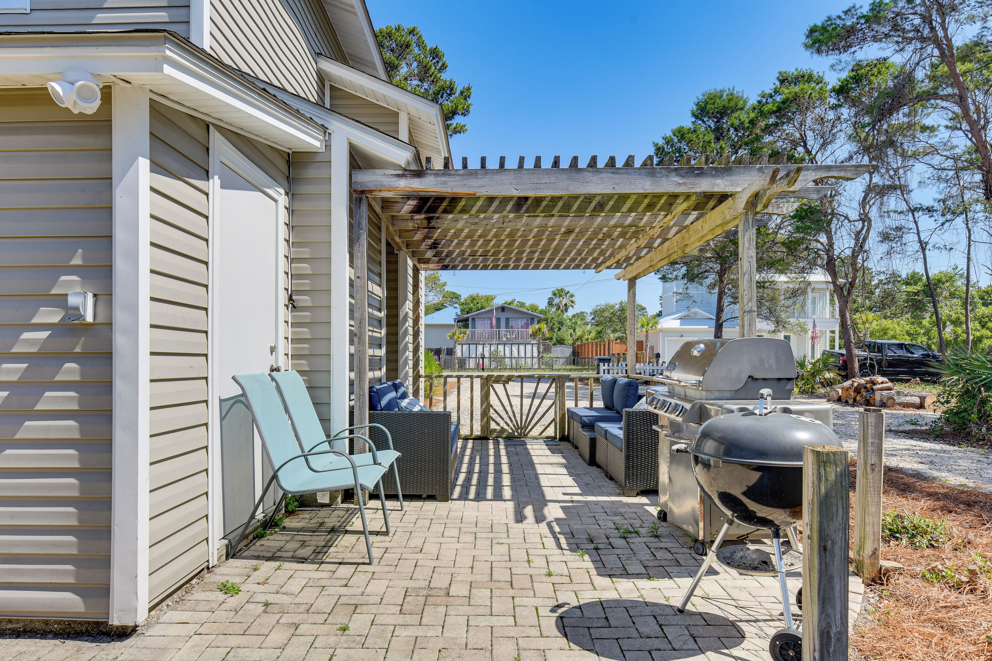 Eine überdachte Terrasse mit Gartenmöbeln, einem Grill und einer Pergola.